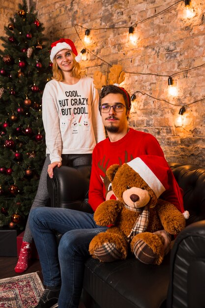 Молодая пара празднует Рождество с плюшевым мишкой