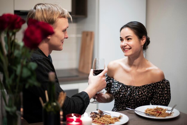 一緒に昼食とワインを飲みながらバレンタインデーを祝う若いカップル