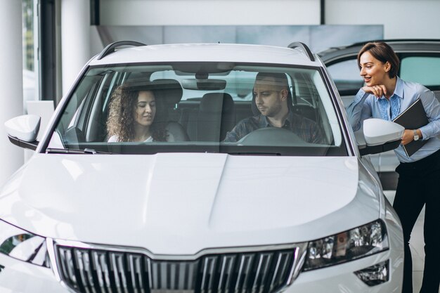 Young couple choosing a car in a car show room