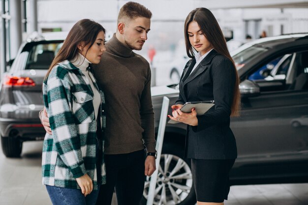 車のショールームで車を選ぶ若いカップル