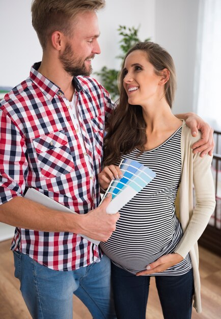 Young couple choosing color for baby's room