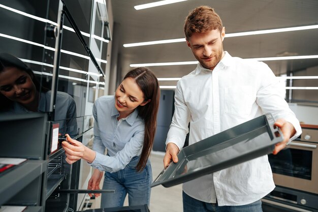 Young couple choosing new electric oven in hypermarket