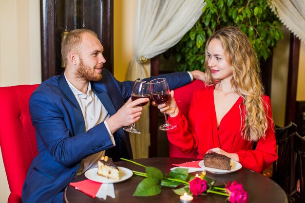 Young couple clanging glasses at table in restaurant 