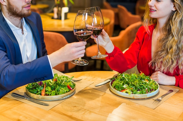 Free photo young couple clanging glasses at table