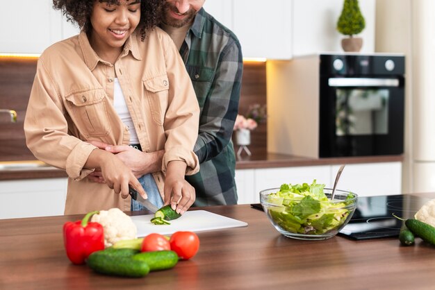 Young couple cutting cucumbers together