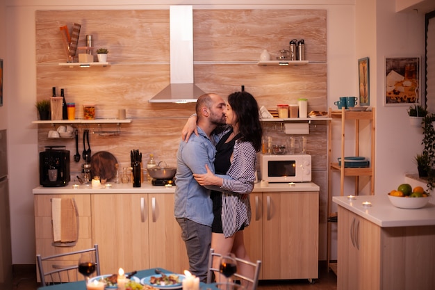 Giovane coppia che balla in cucina durante una cena romantica