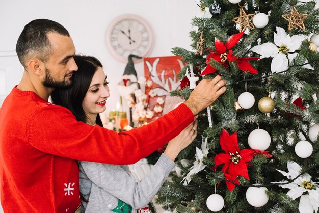 Free photo young couple decorating christmas tree