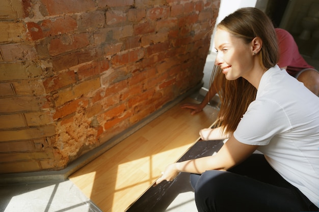 Giovani coppie che fanno insieme riparazione dell'appartamento. uomo e donna sposati che fanno rifacimento o ristrutturazione della casa