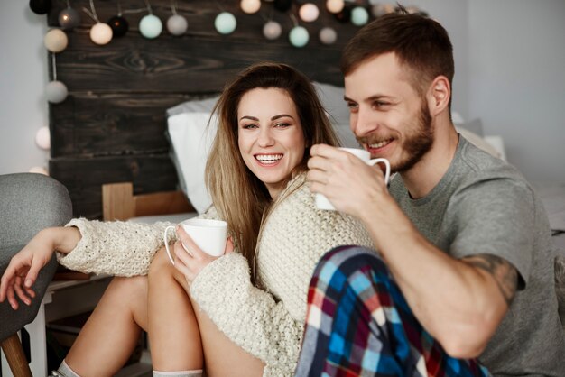 ベッドでコーヒーを飲む若いカップル