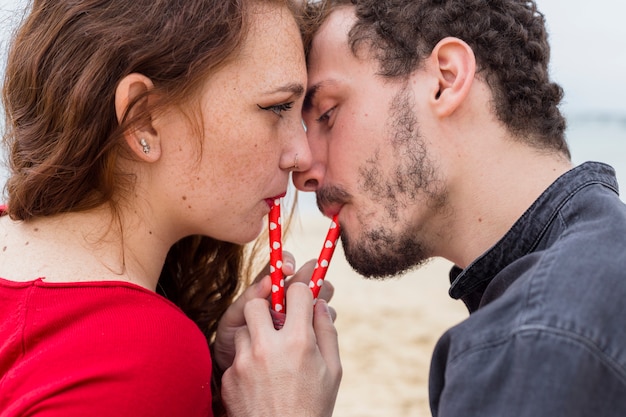 Free photo young couple drinking from bottle with straws