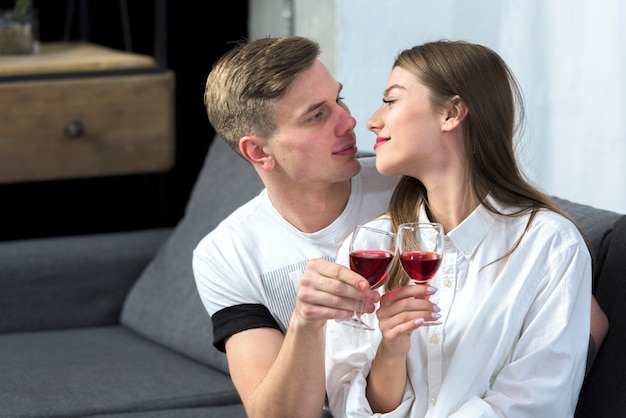 Молодая пара пьет вино на диване