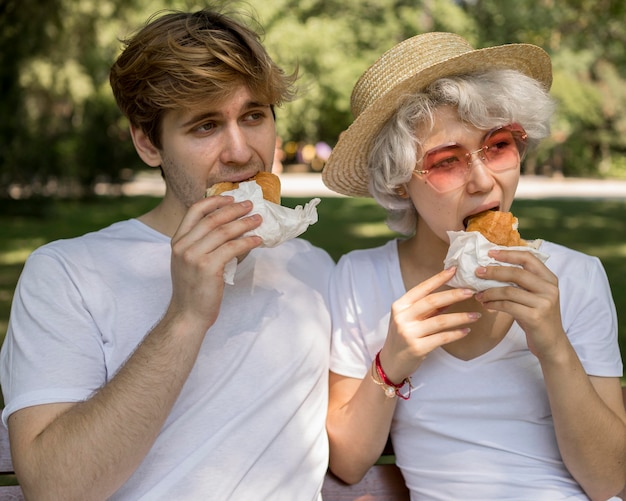 Young couple eating burgers together in the park