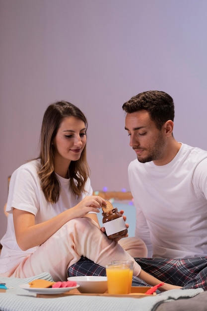 Young couple eating sweets in bed