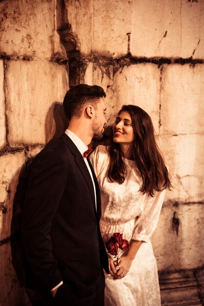 Young couple in elegant clothes leaning on wall