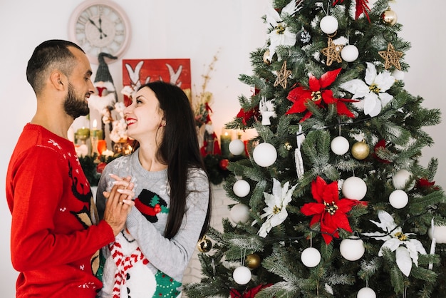 Giovane coppia abbracciando vicino albero di natale