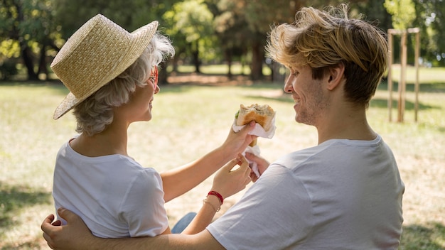 Молодая пара вместе наслаждаются гамбургерами в парке