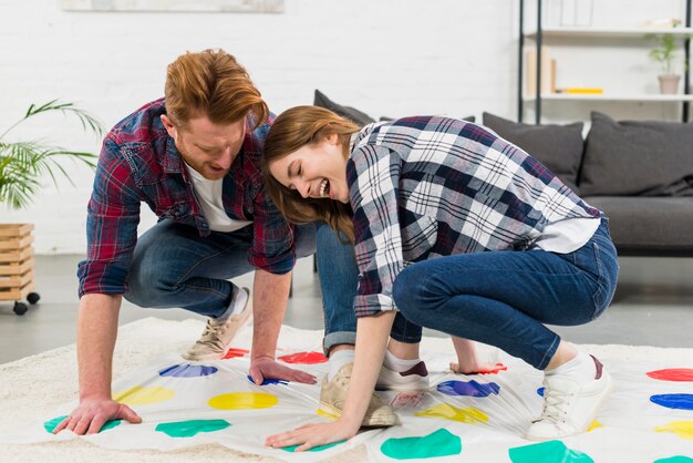 Young couple enjoying the color dot game on carpet at home