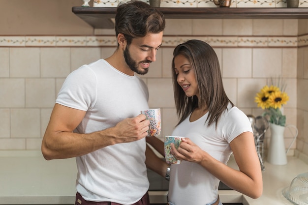 Free photo young couple enjoying hot beverage in kitchen