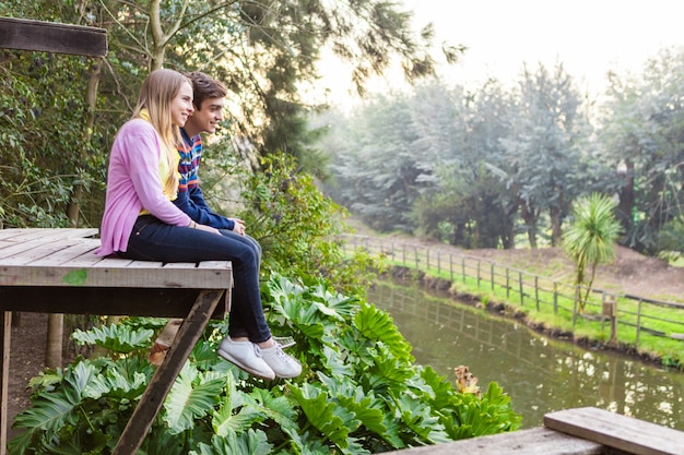 Free photo young couple enjoying nature sitting on a board