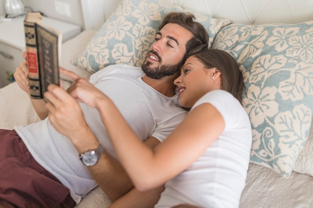 무료 사진 침대에서 독서를 즐기는 젊은 부부