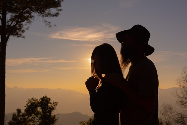山で夕日を楽しむ若いカップル