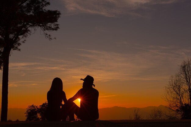 山で夕日を楽しむ若いカップル