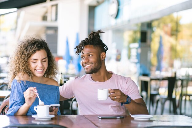 コーヒーショップで一杯のコーヒーを飲みながら一緒に楽しんでいる若いカップル。