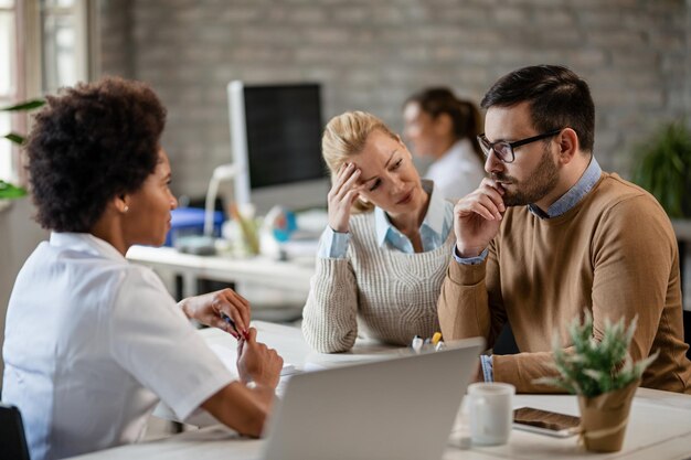 Young couple feeling worried after talking to an African American doctor during medical appointment