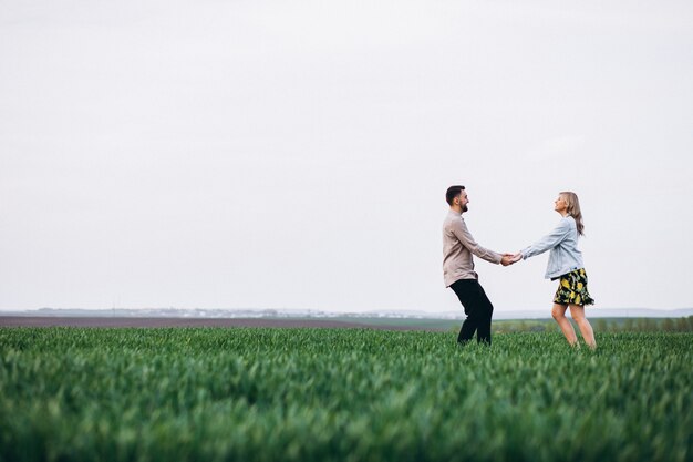 Young couple in the field with green grass