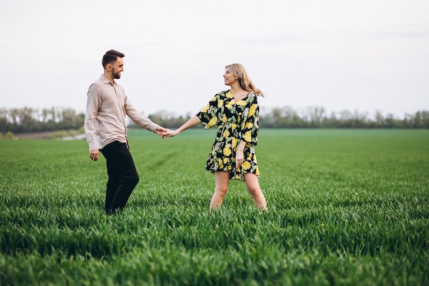 Young couple in the field with green grass