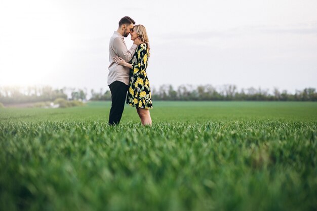 Young couple in the field with green grass