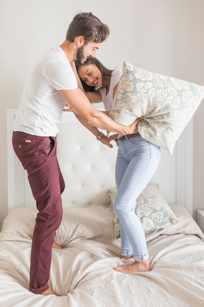 Молодая пара борется с подушками