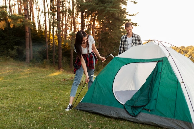 Молодая пара, устанавливающая палатку на природе