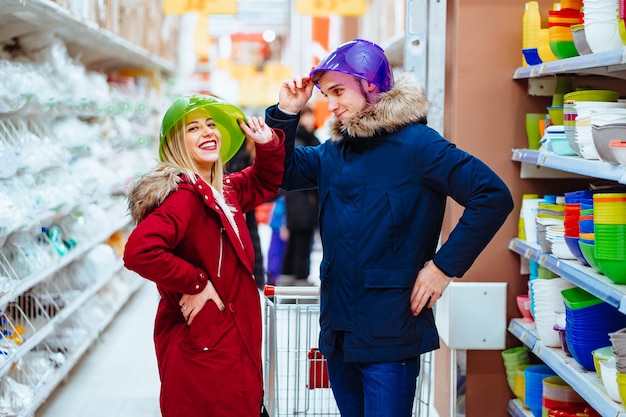 Young couple fooling around with bowls in a supermarket