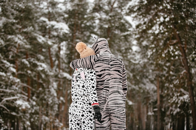 Молодая пара в смешные костюмы животных, обниматься на фоне снежного леса.