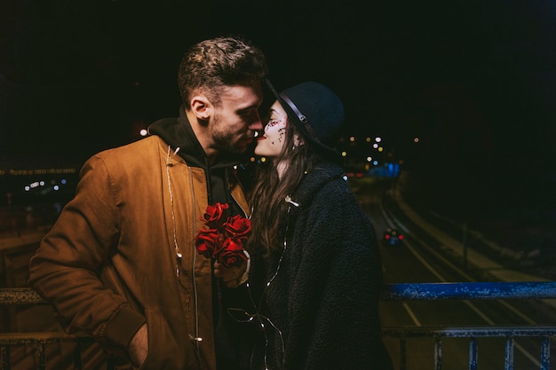 Young couple in garland kissing in dark street