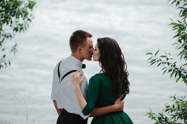 Giovani coppie che dà un bacio vicino al lago