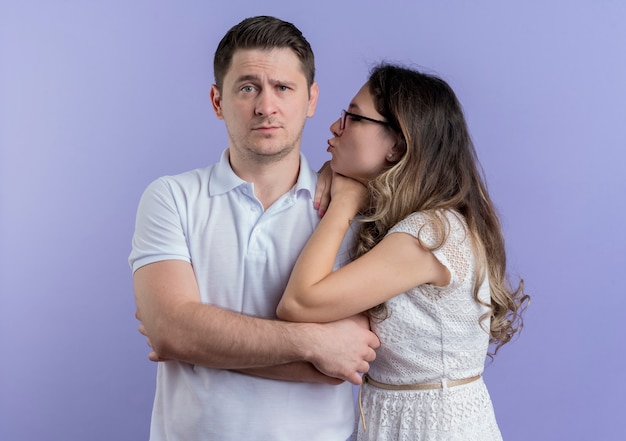 Young couple happy woman looking at her beloved man going to kiss over blue