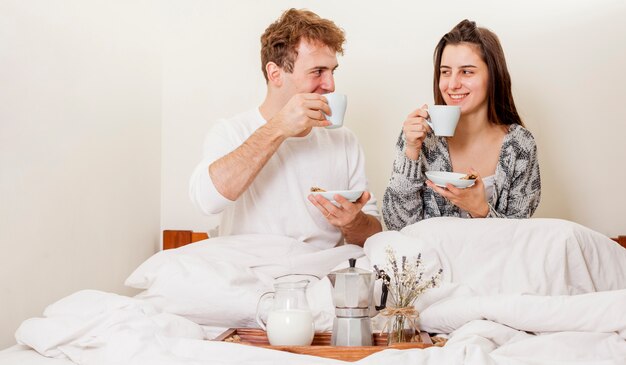 ベッドで朝食を持っている若いカップル