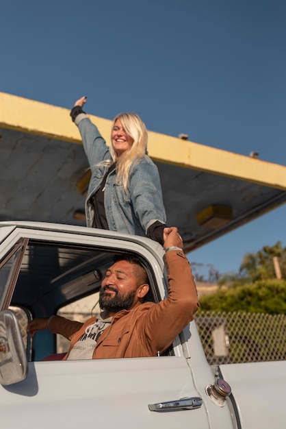 Free photo young couple having fun on their car trip with woman in the back trunk