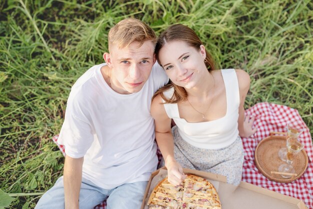 Молодая пара, пикник на поле подсолнечника на закате