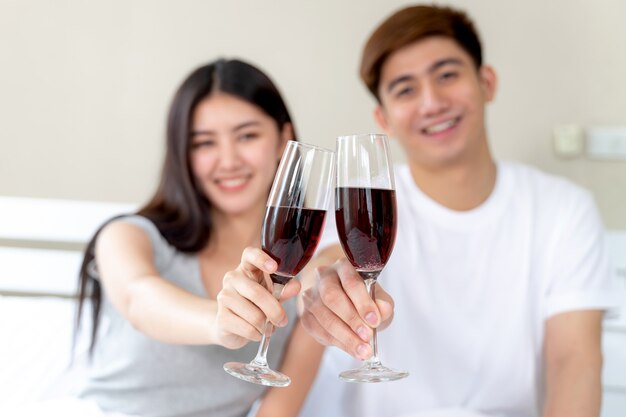 Молодая пара держит бокал вина в спальне