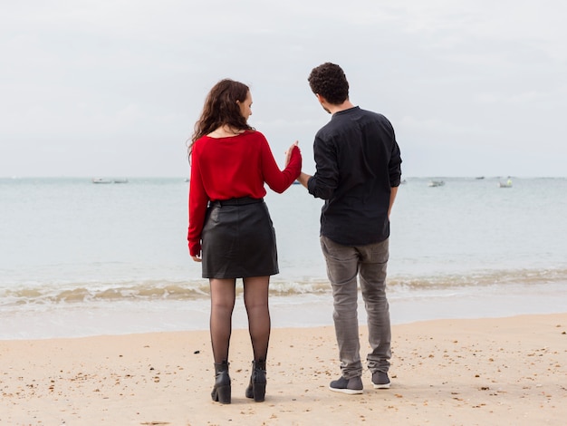 Young couple holding hands on sea shore 