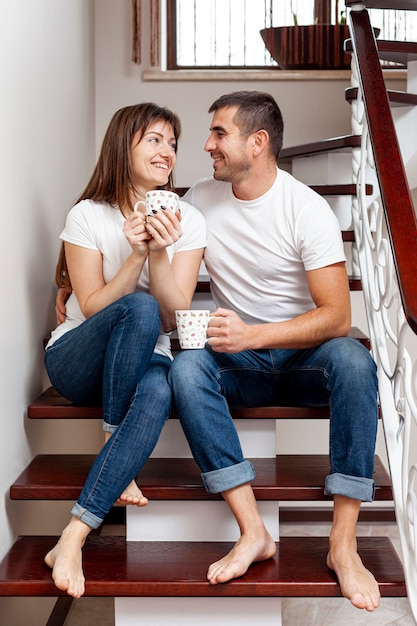 Молодая пара, держась за руки и сидя на лестнице