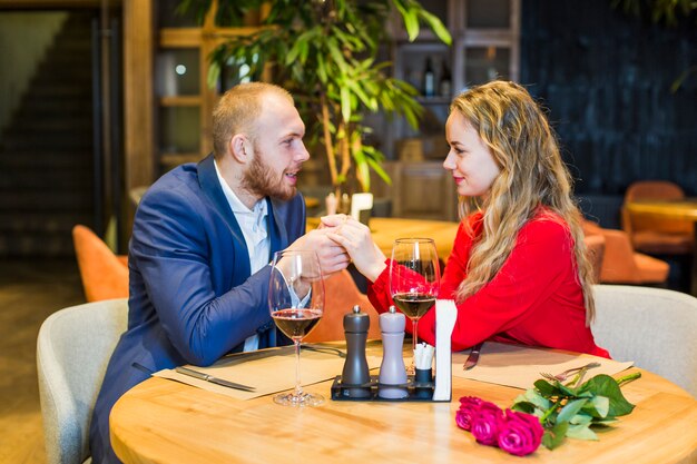 Free photo young couple holding hands at table