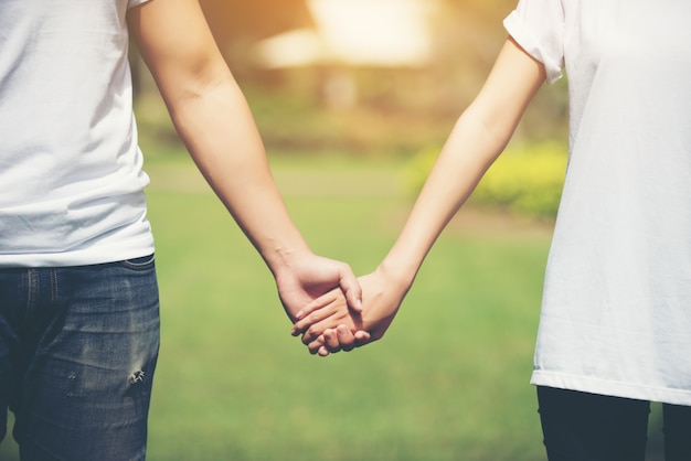 Free photo young couple holding hands walking away together