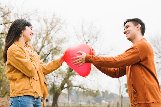 Free photo young couple holding heart shaped balloon