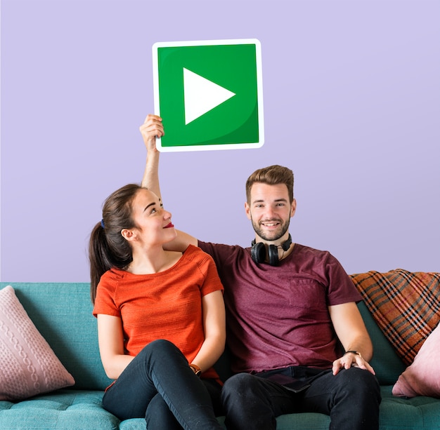 Young couple holding a play button icon