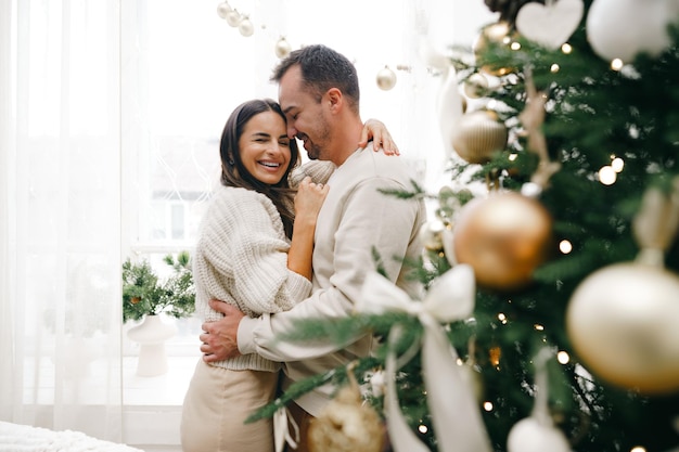 Young couple hugging near christmas tree at home