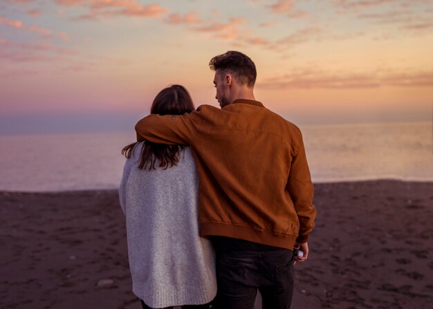 Young couple hugging on sandy sea shore in evening